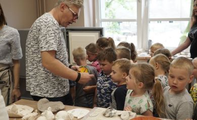 Prowadzący pokazuje dzieciom, wcześniej powstałe prace.