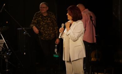 Na pierwszym planie Urszula Dudziak śpiewająca na scenie, natomiast na drugim planie dwóch artystów 