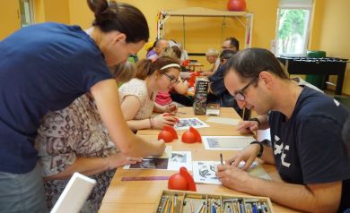 Uczestnicy zajęć rzeźbią matryce ze wzorami do odbijania farby na koszulkach.