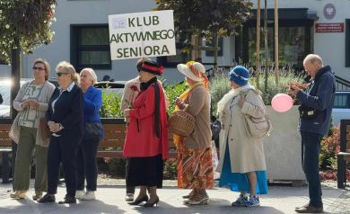 Na zdjęciu grupka osób z tabliczką z napisem ,,Klub aktywnego seniora'.