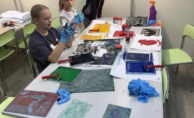 Trzy dziewczynki przy stole, na którym znajdują się różne kolorowe prace. 