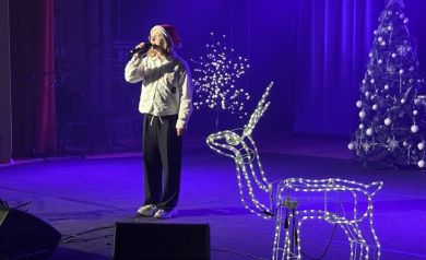 Dziewczyna z czapką Mikołaja na scenie śpiewająca kolędy 