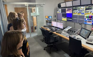 Młodzież w pomieszczeniu TVP 3 Opole, gdzie znajduje się dużo monitorów i sprzętu do sterowania kamerami. 