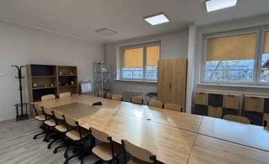 Widok na stoły warsztatowe, regały i witrynę ekspozycyjną w pracowni - powiększ