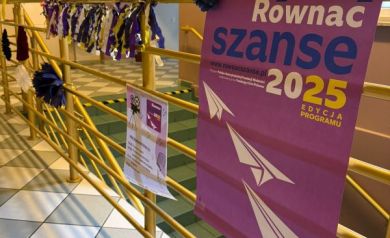 Zdjęcie prezentuje plakaty związane z projektem oraz dekoracje zawieszone na balustradzie.