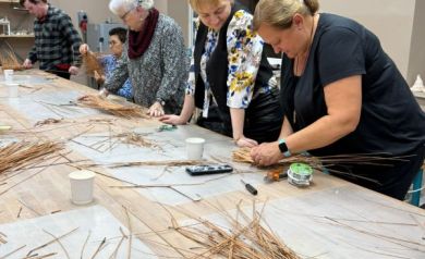 Kobiety i mężczyzna pracują nad swoimi dziełami z wikliny. 