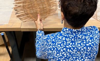 Na zdjęciu kobieta w niebieskiej koszuli w białe kwieciste wzory prezentuje swoją tackę. 