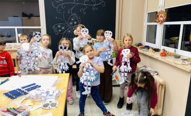 Zdjęcie grupowe dzieci biorących udział w zajęciach. W dłoniach trzymają wykonane przez siebie prace.