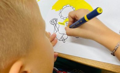 Chłopiec malujący mazakiem na kartce papieru. 