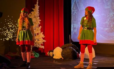 Na zdjęciu znajdują się dwie kobiety przebrane za elfy. Stoją na scenie. 