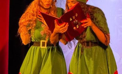 Na zdjęciu dwie kobiety przebrane za elfy. Spoglądają razem w otwarta księgę. 