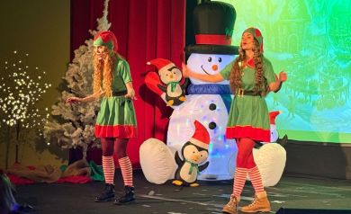 Dwie kobiety przebrane za elfy w trakcie występu. W tle dekoracje świąteczne. 