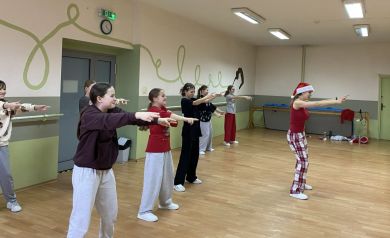 Zdjęcie przedstawia grupę młodych ludzi, dziewcząt, uczestniczących w zajęciach tanecznych w sali tanecznej. 